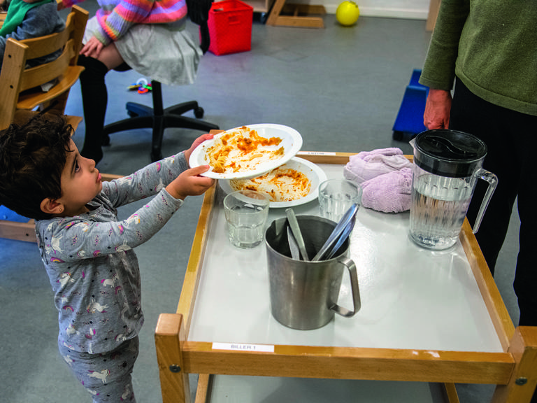 Barn hjælper med tallerknerne i Tumlehuset