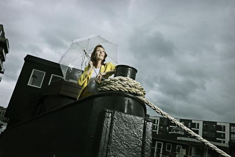 Ditte Hansen i gult jakkesæt på skib med paraply i dårligt vejr