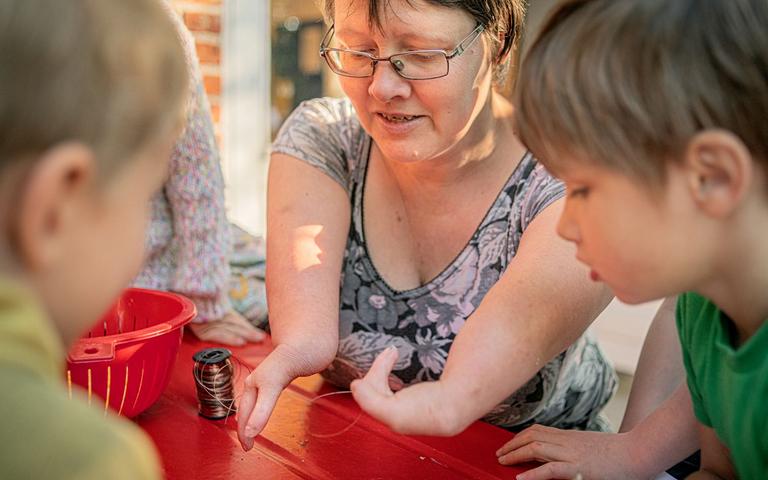 Pædagog Charlotte Andersen sidder sammen med to børn.