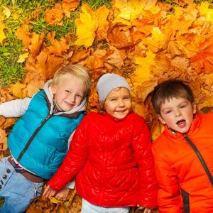 Børn ligger i efterårsblade