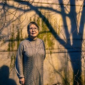 Pædagog Amalie Dorthe Pedersen står foran en væg. Skyggen af et træ omkranser hende.