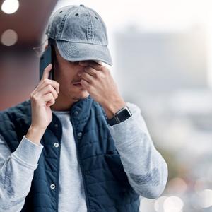 Mand med bekymret mine og grå kasket taler i telefon