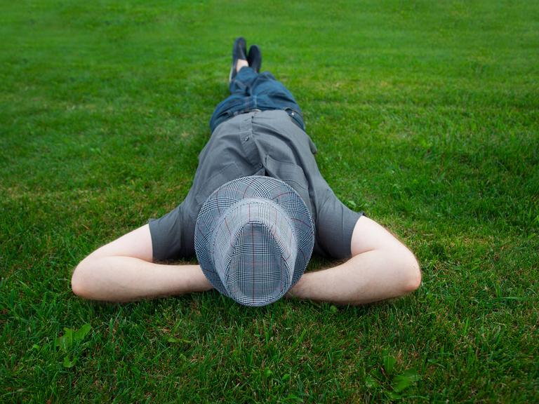 mand med hat ligger på græsplæne