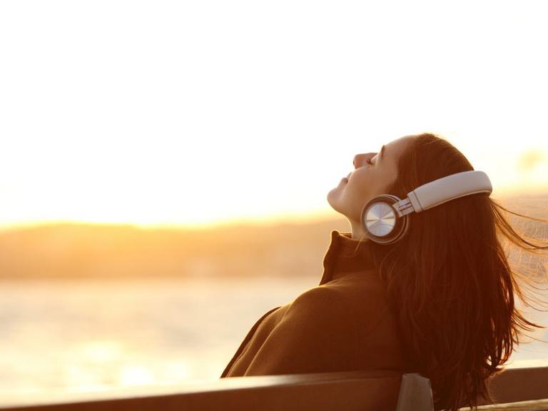 Kvinde lytter til podcast i solskin