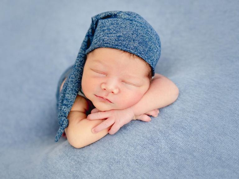 Baby sover med blå nathue