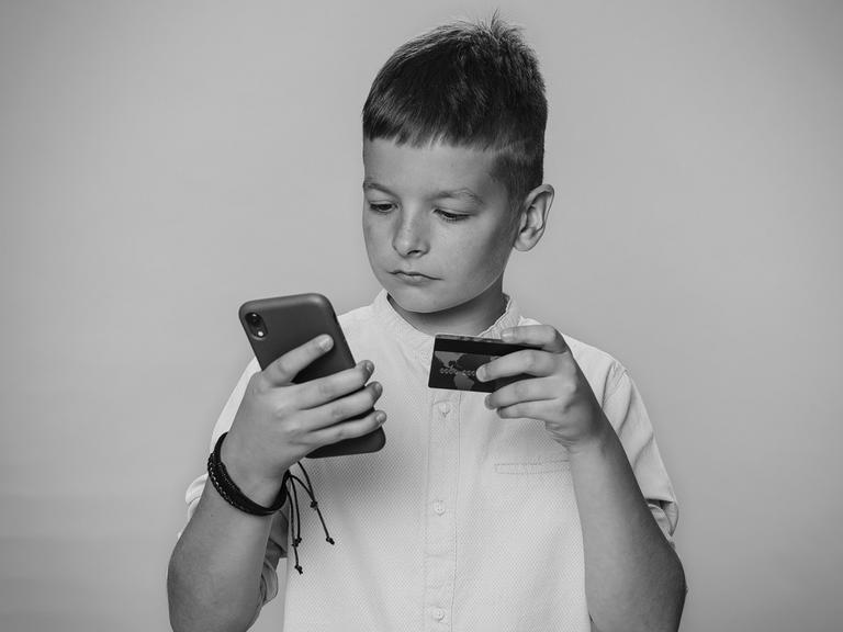 En dreng holder en telefon og et kreditkort