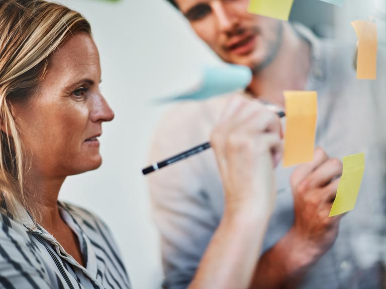 Kvinde og mand skriver på post-it-sedler