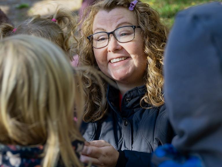 Pædagog Majbritt Degn Kallehauge smiler, omringet af børn