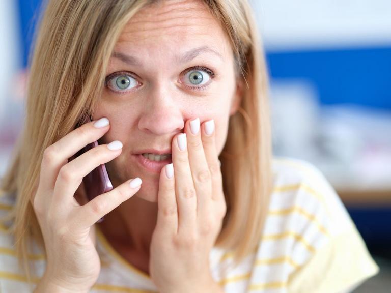Kvinde ser forundret ud og holder telefon til øret