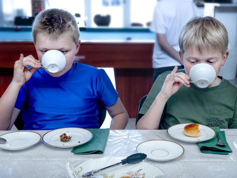To drenge drikker te og stritter med lillefingrene