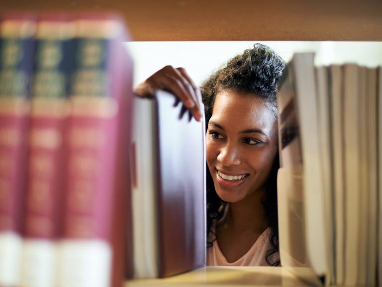 kvindelig pædagog smiler og kigger på bøger i et bibliotek