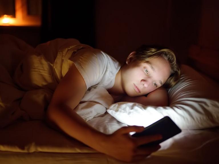 En dreng ligger og kigger på sin mobil