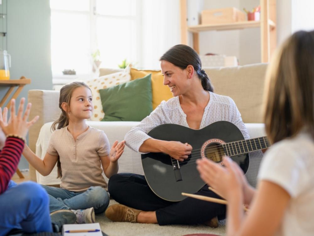 Kvinde spiller guitar for børn