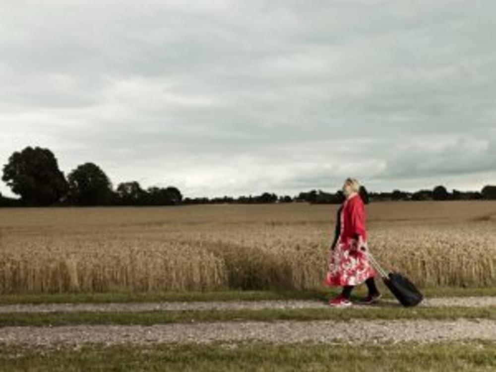 foto af kvinde med kuffert ved en kornmark