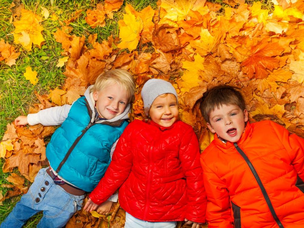 Børn ligger i efterårsblade