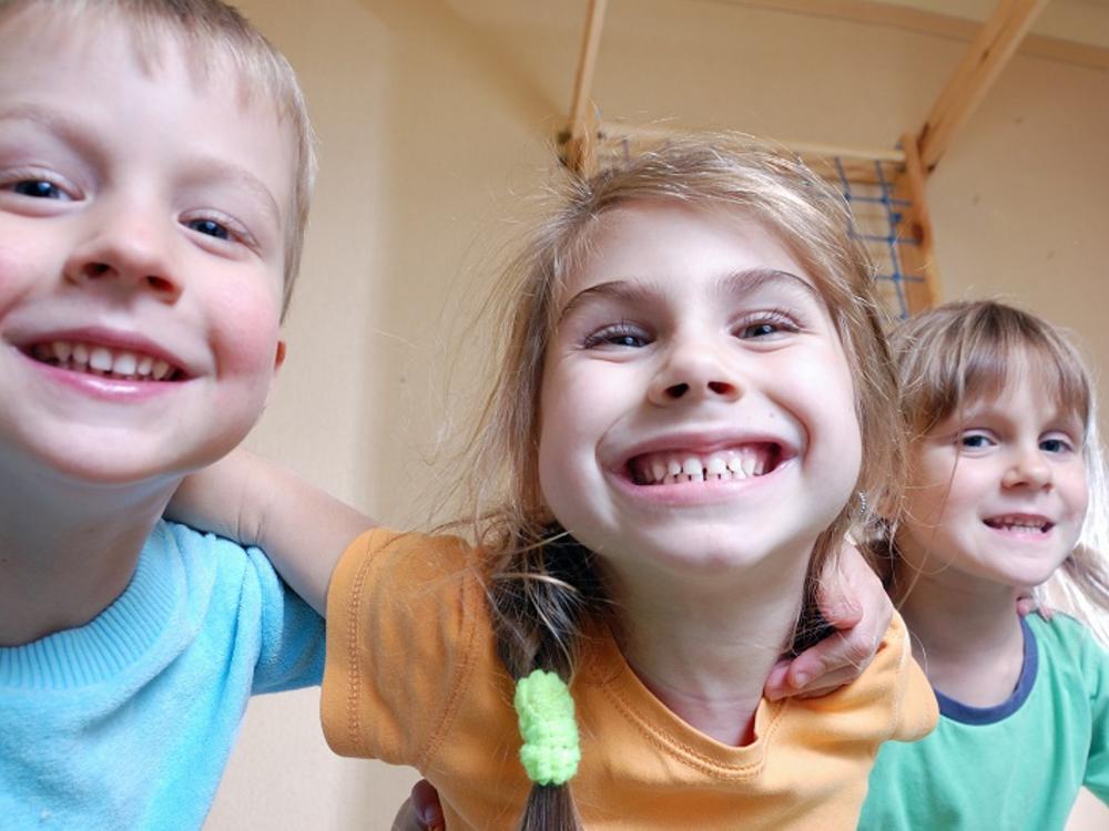 Tre glade børn med store smil 
