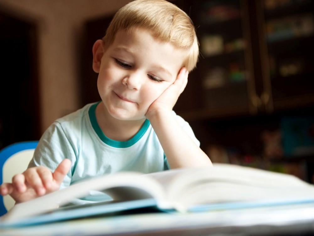 Foto af lille dreng, der kigger i en bog.