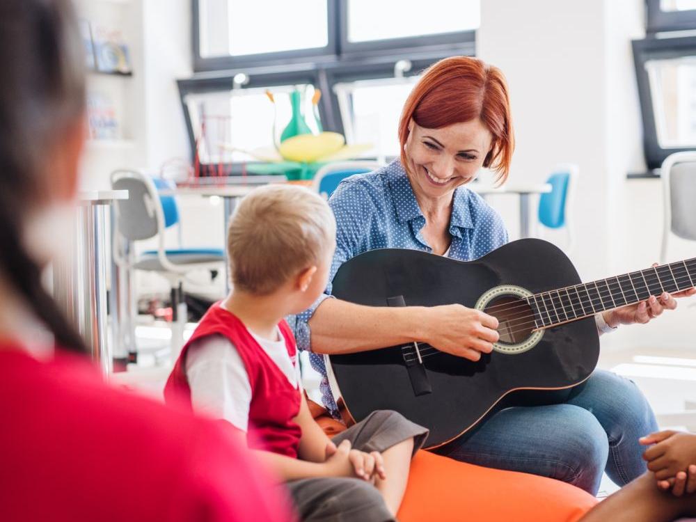 Kvindelig pædagog spiller guitar