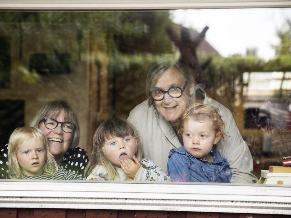 To pædagoger kigger ud ad vindue sammen med tre børn