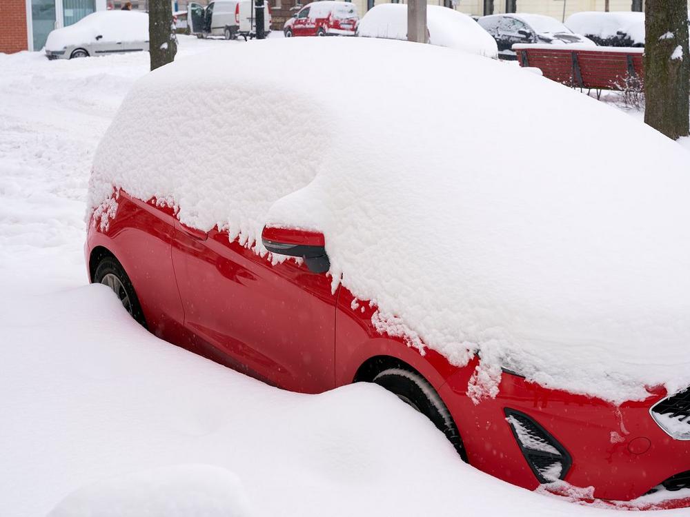 En rød personbil sidder fast i sneen
