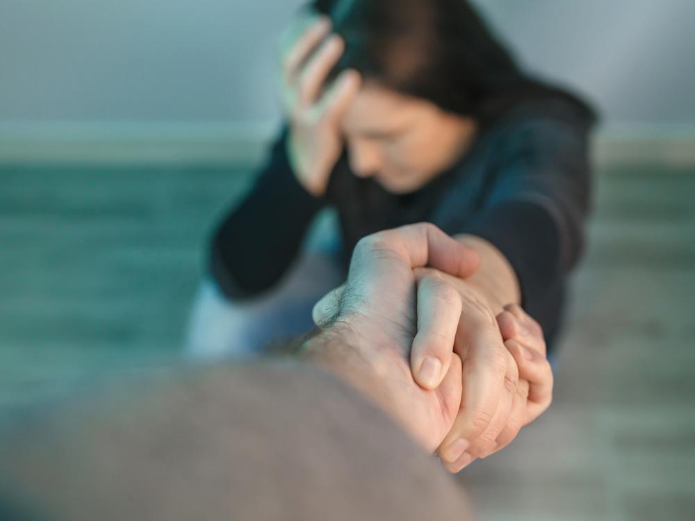 mand rækker en hånd til stresset kollega på gulvet