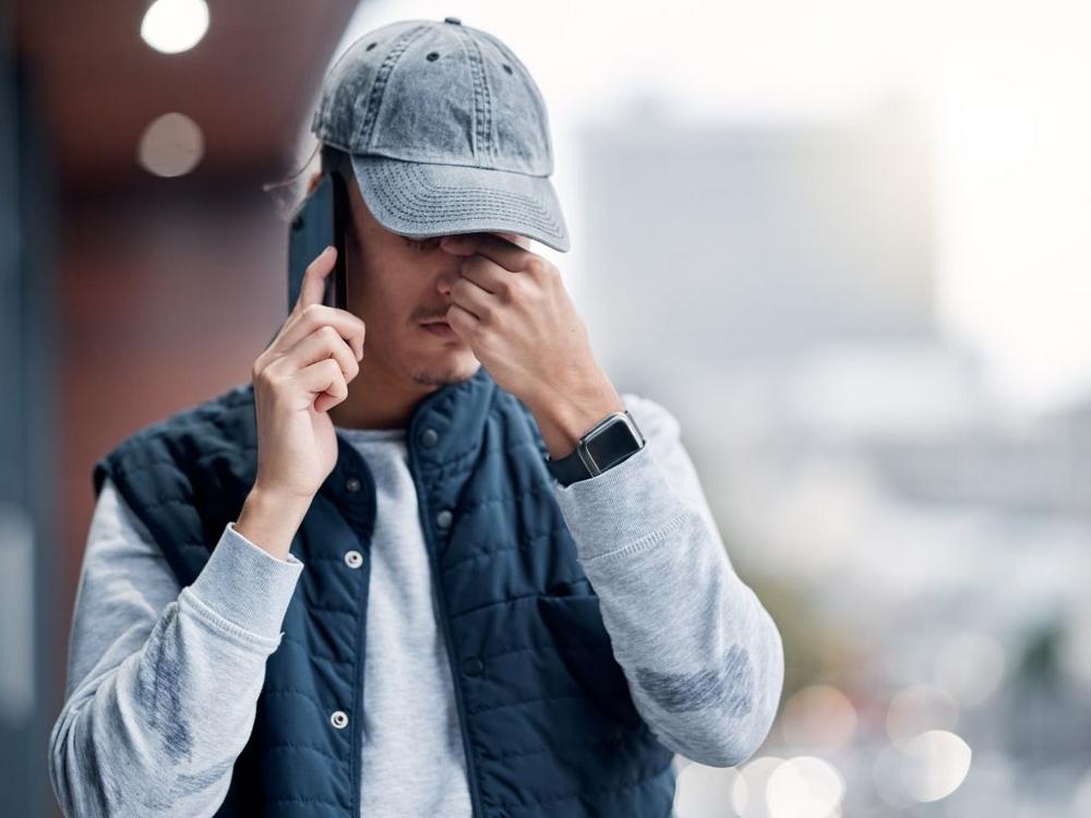 Mand med bekymret mine og grå kasket taler i telefon