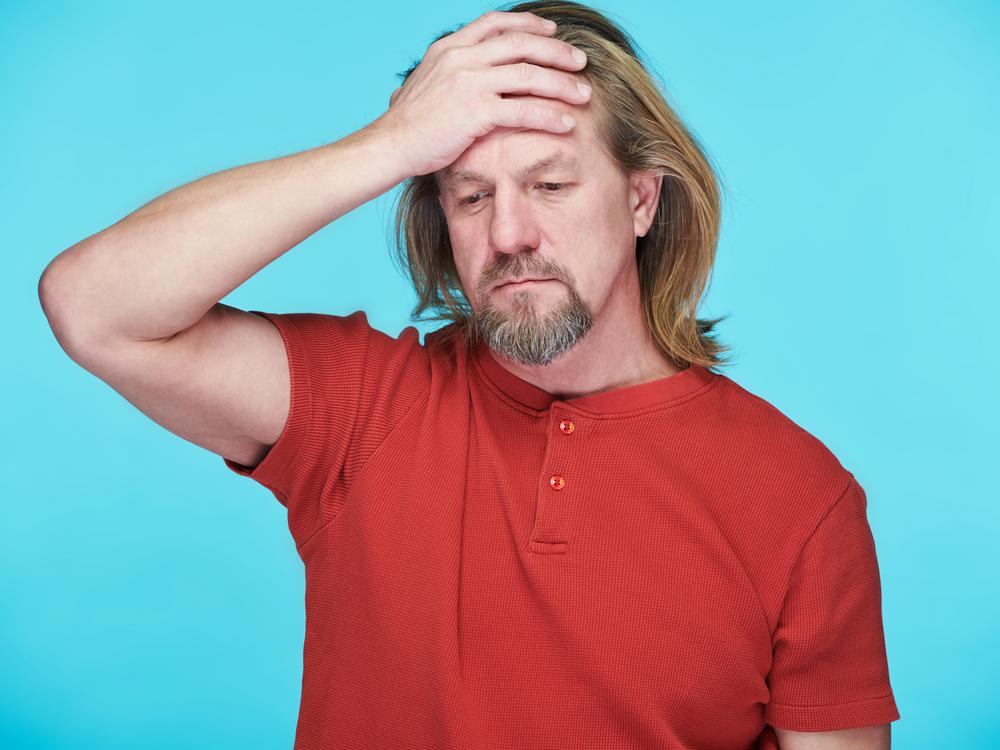 mandlig pædagog tager sig til hovedet, ramt af moralsk stress
