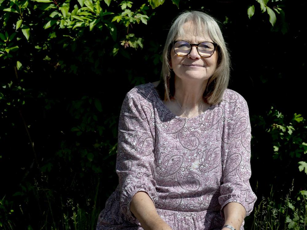 Pædagog Mette Westergaard sidder foran en hæk