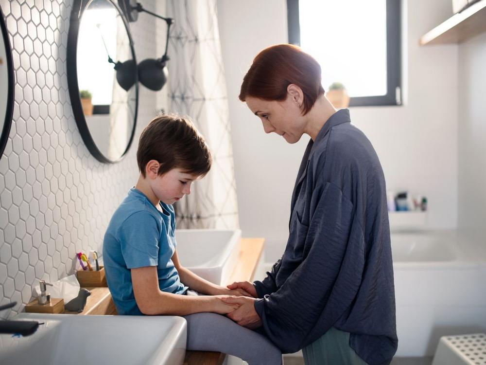 Mor trøster sin søn på badeværelse