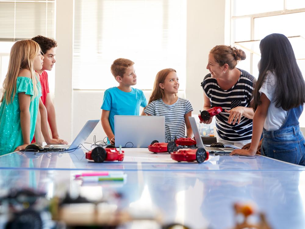 kvindelig pædagog og børn leger med AI