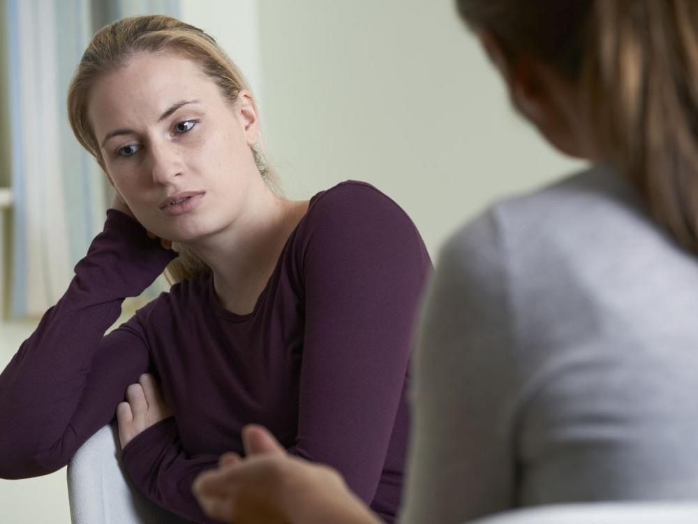 Kvinde taler med anden kvinde, ser trist ud