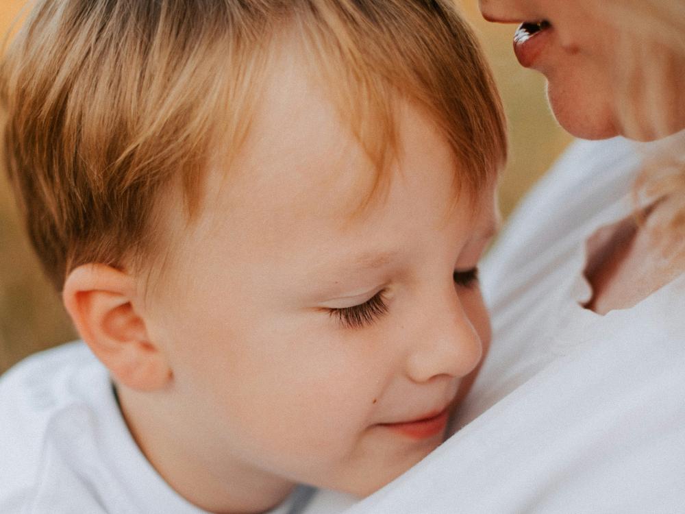 lille dreng ser tryg ud i favnen på pædagog