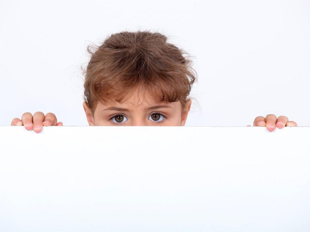 Barn kigger op over kanten af et bord