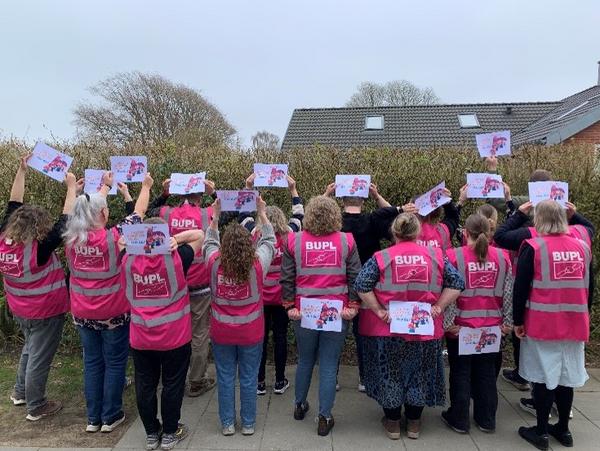 Billede af mennesker med ryggen til, der holder skilte om at de har stemt om OK26