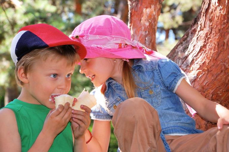 Pige og dreng i træ spiser is