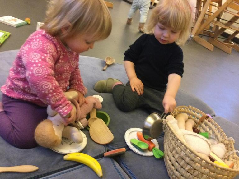Pige og dreng leger med dukker