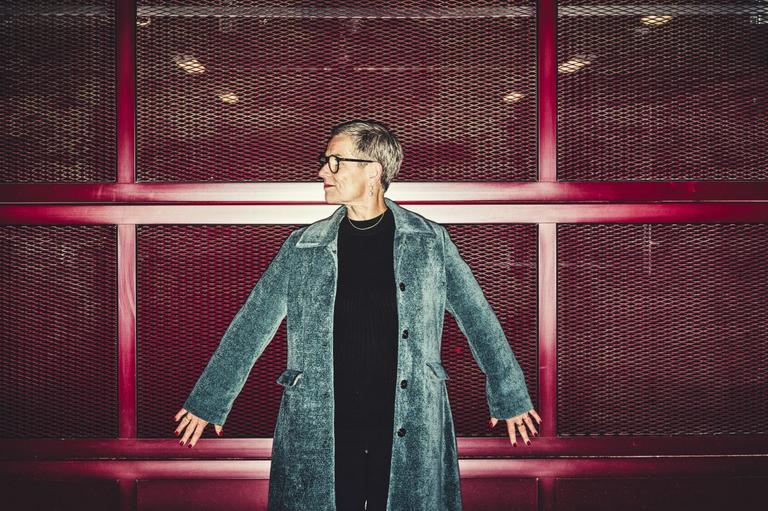 Psykolog og forfatter Rikke Høgsted står op ad rødt gitter